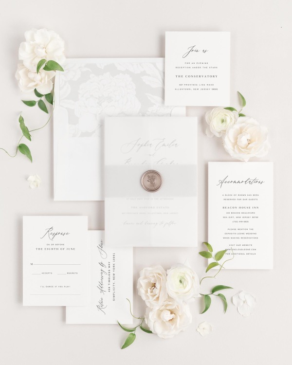 Sophia wedding invitations flat lay with soft gray blooms liner, soft gray belly band, translucent vellum jacket, and bronze posy wax seal.
