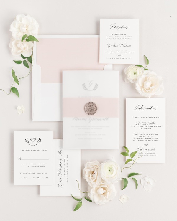 Wreath Monogram wedding invitations flat lay with rose gold solid liner, rose gold belly band, translucent vellum jacket, and bronze florette wax seal.