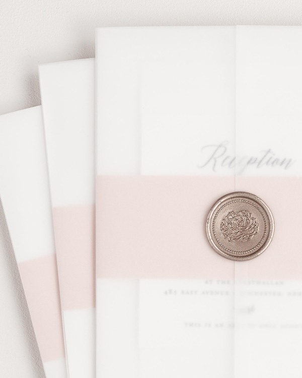 Wreath Monogram wedding invitation with a rose gold belly band, translucent vellum jacket, and bronze florette wax seal.